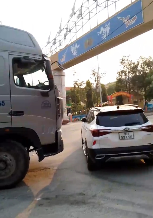 Xe ô tô màu trắng được cho là của gia đình ông Võ Quốc Huy, Đội trưởng Đội Hình sự, Công an huyện Hậu Lộc, chắn ngang đầu xe tải. Ảnh cắt từ clip
